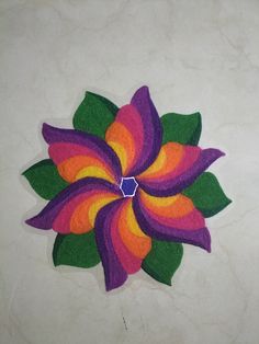 a colorful flower made out of felt sitting on top of a white tablecloth covered floor