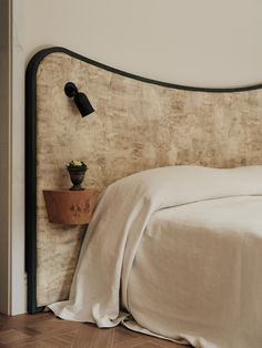 a bed with a white comforter and two black lamps on the wall next to it