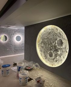 there are some buckets on the floor in front of a wall with an image of the moon