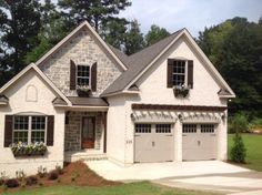 a white brick house with two garages and three windows