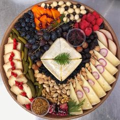 a platter filled with different types of cheeses, fruits and crackers on top of each other