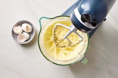 a blender filled with yellow liquid next to eggs