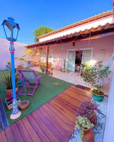 an outdoor area with wooden decking, potted plants and lights in the background