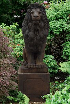 a statue of a lion sitting on top of a stone block in front of bushes