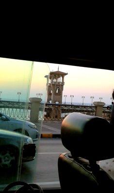 the view from inside a car looking out at an old building and ocean in the distance