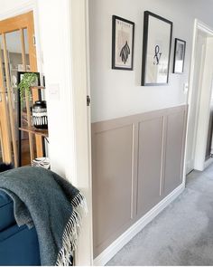 a living room filled with furniture and pictures on the wall next to a doorway that leads to a hallway