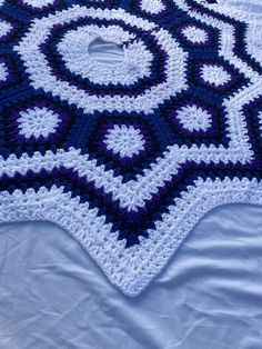 a blue and white crocheted blanket on top of a bed