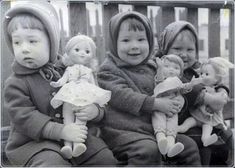 black and white photograph of four children holding dolls