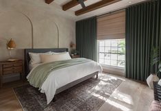 a bedroom with a large bed and green drapes on the windowsill, along with a rug