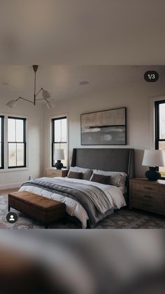 a large bed sitting in the middle of a bedroom next to two lamps and windows