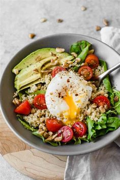 a bowl filled with salad and topped with an poached egg on top of it