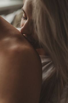 a close up of a person laying on a bed with their arm around the back of a woman