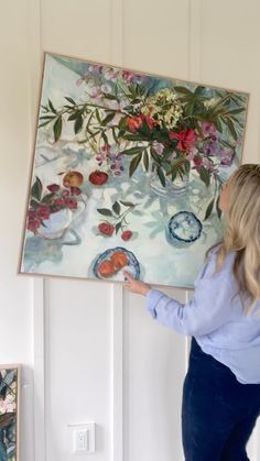 a woman is painting flowers on the wall