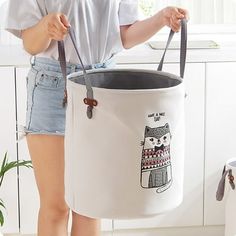 a woman is holding a bucket with a cat on it and the handles are open