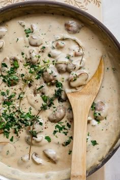 a pan filled with mushrooms and parsley next to a wooden spoon