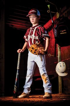 a young boy holding a baseball bat and wearing a catchers mitt