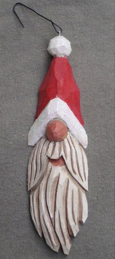 a red and white santa claus ornament hanging from a hook on a wall