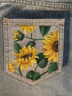 the back pocket of a pair of jeans with sunflowers painted on it