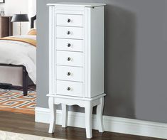 a white chest of drawers next to a bed