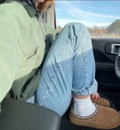 a woman sitting in the passenger seat of a car with her feet on the floor