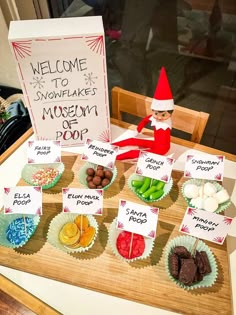 an elf is sitting on a table with cupcakes and marshmallows