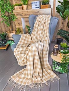 a plaid blanket sitting on top of a chair next to potted plants