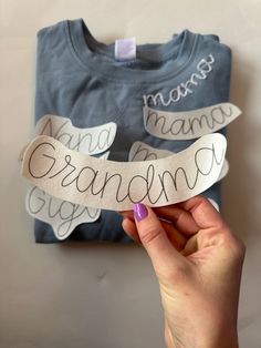 a person holding up a piece of paper with the word grandma on it