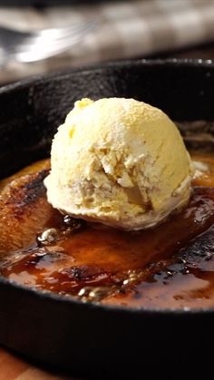 a skillet with some ice cream in it and sauce on the table next to it