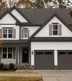 a white house with two garages and brown shutters on the front door is shown