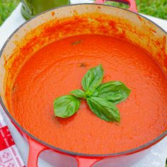 a pot of tomato soup with basil leaves on top