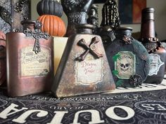 some bottles are sitting on a table with skulls and bones around them, all decorated in different colors