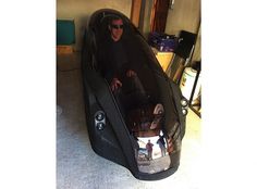 a man sitting inside of a black car in a garage