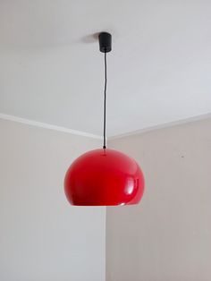 a red light hanging from the ceiling in a room with white walls and flooring