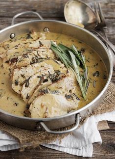 a pan filled with chicken covered in gravy and garnished with herbs