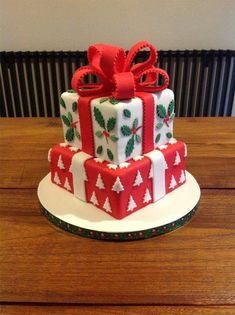 a three tiered cake decorated with red and white wrapping presents on top of a wooden table