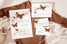 the wedding stationery is laid out on top of some white feathers and brown sweaters