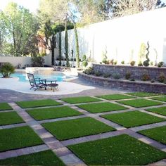 an outdoor patio with grass on the ground and a swimming pool in the back yard