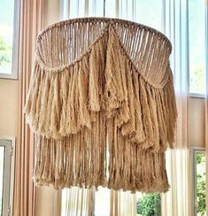 a chandelier hanging from the ceiling in a living room with curtains and windows