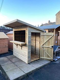 a wooden outhouse sitting on the side of a road next to a fenced in area