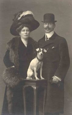 an old black and white photo shows a man and woman with a small dog sitting on a table