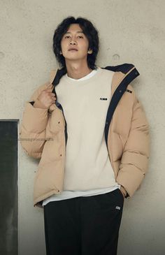 a young man standing in front of a wall