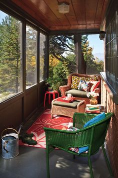 a screened porch with wicker furniture and red rug on the floor next to it