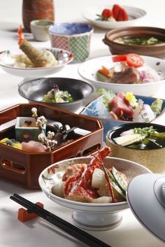 a table topped with bowls filled with different types of food and chopsticks on top of it