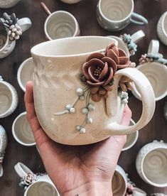 a hand holding a coffee cup with flowers on it