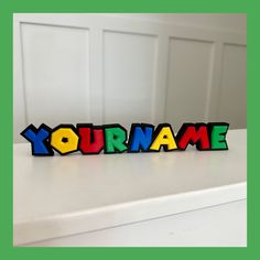 a wooden name sign with the word'your name'spelled in multicolored letters