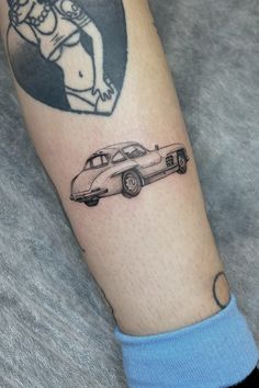 a man's arm with a tattoo on it and a car in the background