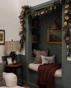 a room with green painted walls and white furniture, decorated with garlands on the windowsill