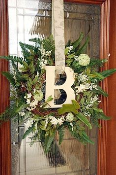 a wreath with the letter b on it is hanging in front of a glass door