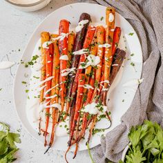 carrots on a plate with ranch dressing drizzled over them and garnished with parsley