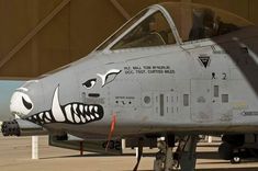 a fighter jet with an angry face painted on it's side